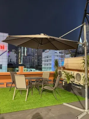 a table and chairs under an umbrella on a rooftop at StarQ Hotel Bukit Bintang in Kuala Lumpur