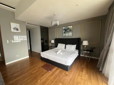 a bedroom with a bed with white sheets and wood floors at Anggun KL MY in Kuala Lumpur