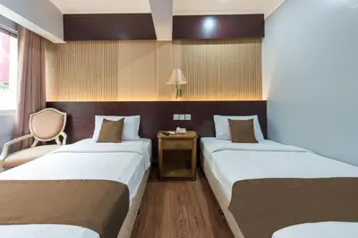 a hotel room with two beds and a chair at Grand Orchard Hotel Premier in Kuala Lumpur