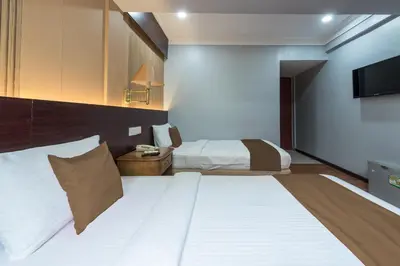 a hotel room with two beds and a television at Grand Orchard Hotel Premier in Kuala Lumpur
