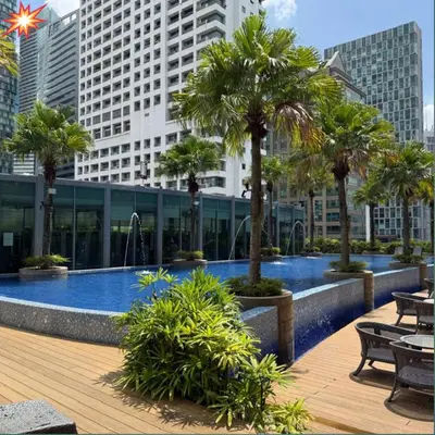 a swimming pool with palm trees in a city at vortex klcc apartment by Dream NIGHT in Kuala Lumpur