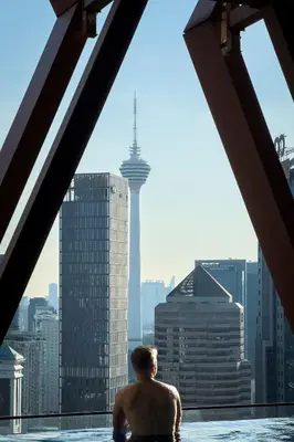 a man sitting in a swimming pool looking at the city at Scarletz Suites KLCC by KAN's in Kuala Lumpur
