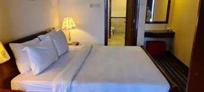 a bed with white sheets and pillows in a room at Raymond Suites at Times Square kuala Lumpur in Kuala Lumpur