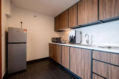 a kitchen with wooden cabinets and a refrigerator at UNA Residence By Feel Home Malaysia opposite Sunway Velocity Mall in Kuala Lumpur