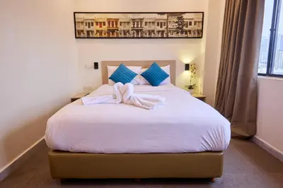 a bedroom with a bed with white sheets and blue pillows at Hotel Bintang Kuala Lumpur in Kuala Lumpur