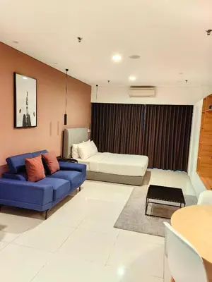 a living room with a blue couch and a bed at Summer Suites KLCC By GRAND CENTRAL in Kuala Lumpur