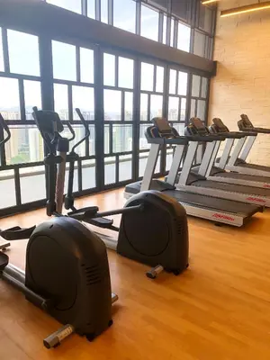 a gym with a row of tread machines in a room at M and S Suite at Societe Suites Sri Hartamas, Mont Kiara in Kuala Lumpur