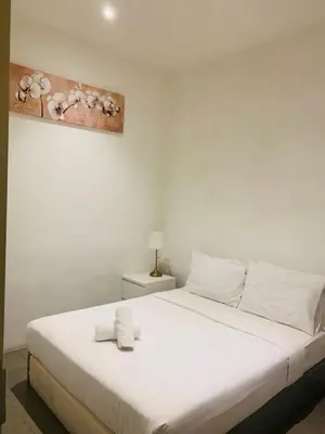 a bedroom with a white bed with a painting on the wall at KL Sentral Bangsar Suites EST by Inam Suites in Kuala Lumpur