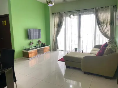 a living room with green walls and a couch and a tv at Spritz Empire Regalia Suites & Residence in Kuala Lumpur