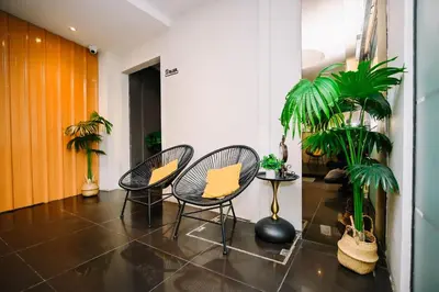 a hallway with two chairs and a table and palm trees at Swing & Pillows - Central Market Kuala Lumpur in Kuala Lumpur