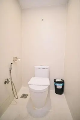 a white bathroom with a toilet and a trash can at Swing & Pillows - Central Market Kuala Lumpur in Kuala Lumpur