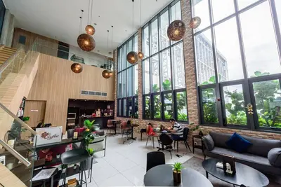 a person sitting at a table in a room with windows at CL24A 5-6pax KLCC Sky Pool Condo in Kuala Lumpur