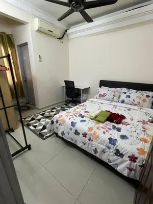 a bedroom with a bed and a chair in it at Indah Putri Homestay in Kuala Lumpur