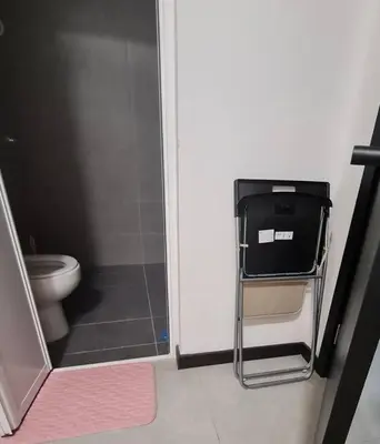 a bathroom with a toilet and a chair in the door at Tiny Studio Suite Near Gleneagles 10 mins to KLCC in Kuala Lumpur