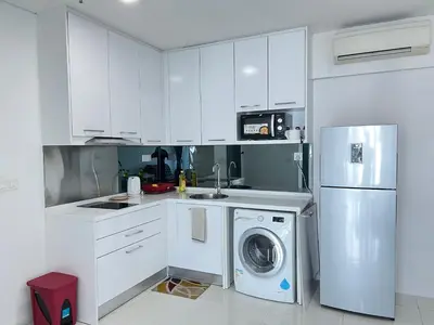 a white kitchen with a washing machine and a refrigerator at Summer Suites KLCC By Victorians in Kuala Lumpur