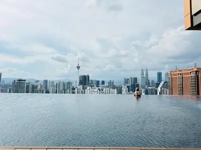 a man sitting in the infinity pool of a building with a city at Smart Home at Lucentia Residence BBCC Lalaport in Kuala Lumpur