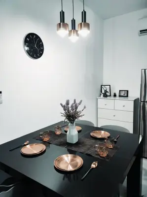 a dining room table with plates and a clock on the wall at Neu suites advance HomeStay klcc in Kuala Lumpur