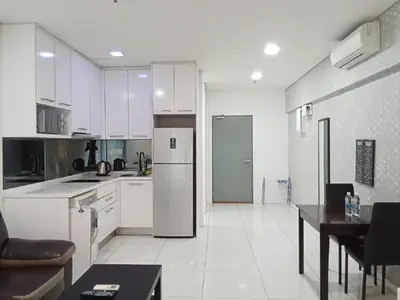 a kitchen with white cabinets and a table and a refrigerator at Diamond Suite KL at Mercu Summer Suite KLCC in Kuala Lumpur