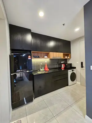 a kitchen with black cabinets and a washer and dryer at Axon Infinity Pool KL in Kuala Lumpur