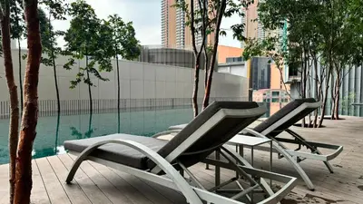 two lounge chairs sitting next to a swimming pool at Springtime 2bedrooms with KLCC view &Gorgeous pool in Kuala Lumpur