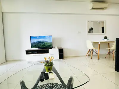 a living room with a tv and a glass table at Summer Suites KLCC by Luna KL in Kuala Lumpur