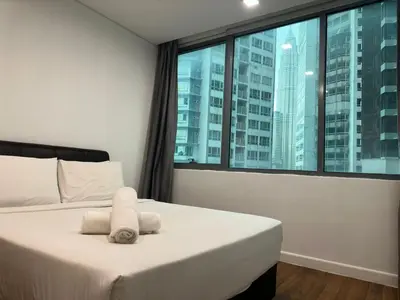 a bedroom with a bed with white sheets and a large window at Summer Suites KLCC by Luna KL in Kuala Lumpur