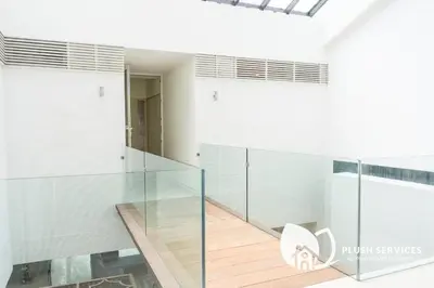 a glass staircase in a white room with a white chair at Damansara Heights by Plush in Kuala Lumpur