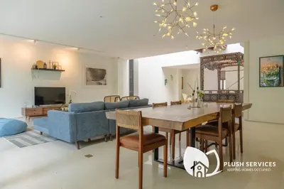a dining room and living room with a table and a couch at Damansara Heights by Plush in Kuala Lumpur