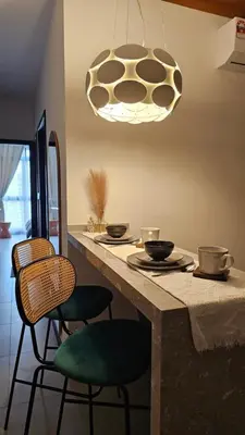 a kitchen with a table with chairs and aendant light at Neu Suites in Kuala Lumpur