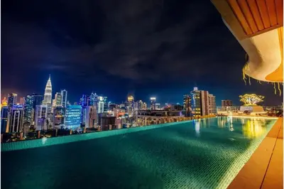 a rooftop swimming pool with a city skyline at night at Ceylonz Suites By Staybliss in Kuala Lumpur