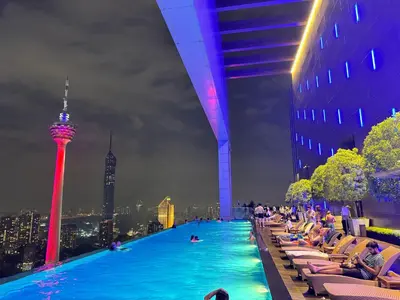 a swimming pool with people sitting in chairs and a city at The Platinum Kuala Lumpur KLCC By Garden Suites in Kuala Lumpur