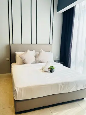 a bed with white sheets and a plant on it at Axon Suite Premium KL in Kuala Lumpur