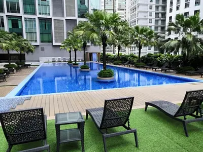 a swimming pool with chairs and palm trees in a building at 2bedroom SOHO SUITE KLCC View by Homeizing in Kuala Lumpur