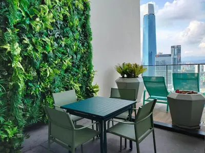 a table and chairs on a balcony with a green wall at Exquisite KL Retreat Pool & Gym High Speed 100MB in Kuala Lumpur