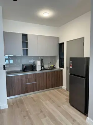 a kitchen with a black refrigerator and wooden cabinets at M Vertica Residence in Kuala Lumpur