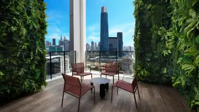 a balcony with chairs and a table and a view of the city at CONTINEW Residence - TRX KL in Kuala Lumpur