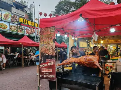 a man cooking a chicken on a grill in a market at Robertson to be opened in Kuala Lumpur