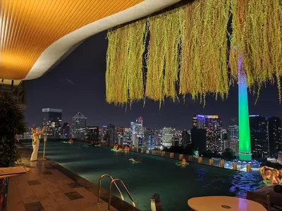 a rooftop pool with a city skyline at night at Staybliss At Ceylonz Suites in Kuala Lumpur