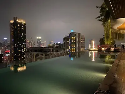 a pool of water with a city skyline at night at Staybliss At Ceylonz Suites in Kuala Lumpur