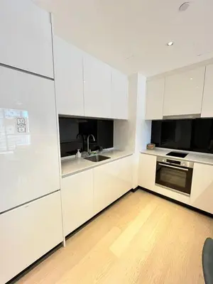 a white kitchen with white cabinets and a wooden floor at Star Residence By M&T in Kuala Lumpur