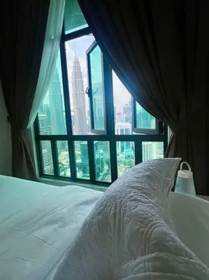 a bed with a view of a city from a window at Legasi High floor 3 BR KLCC view in Kuala Lumpur