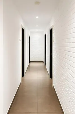 an empty corridor with white walls and black doors at Hotel 1915 Chinatown Kuala Lumpur in Kuala Lumpur
