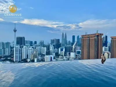 a man standing on the edge of a building overlooking a city at Lucentia BukitBintang KlccView InfinityPool By HeyStay Management in Kuala Lumpur
