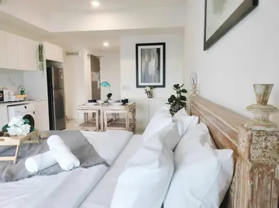 a living room with a bed with white pillows at Charming Haven in Kuala Lumpur 100Mb TRX Mall in Kuala Lumpur