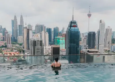 a woman in a infinity pool overlooking a city at Pool Haven Reservations in Kuala Lumpur