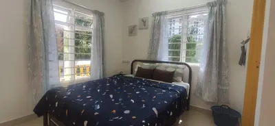 a bedroom with a bed with a blue comforter and two windows at Hostel Room with Private Bathroom in Kuala Lumpur