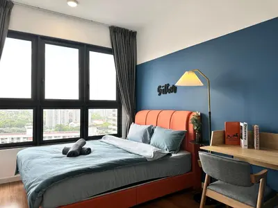 a bedroom with a bed with an orange headboard and a desk at M Vertica, Sunway Velocity Kuala Lumpur by Rverse Suite in Kuala Lumpur