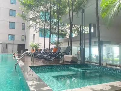 a swimming pool with chairs next to a building at Summer Suites KLCC by apartx in Kuala Lumpur