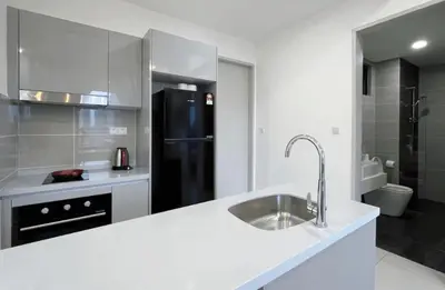 a white kitchen with a sink and a black refrigerator at Trion Kuala Lumpur in Kuala Lumpur