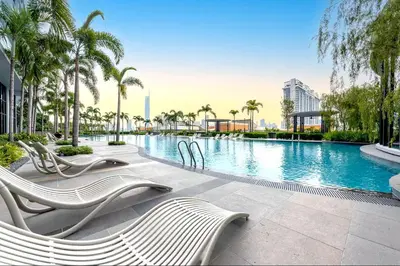 a swimming pool with white chairs and palm trees at Trion Kuala Lumpur in Kuala Lumpur